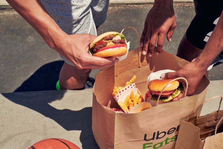 two people are holding sandwiches and basketballs in their hands as they stand on the street