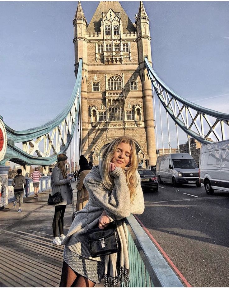 a woman standing on the side of a bridge talking on a cell phone