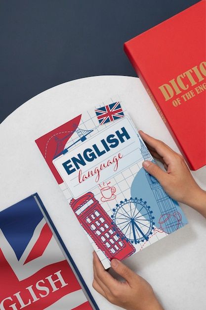 a person is holding up an english language book on a table with flags around it