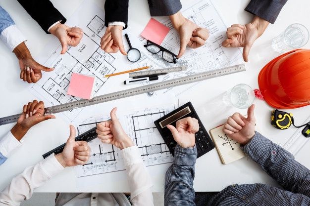 several people sitting at a table with their hands on top of papers and pencils