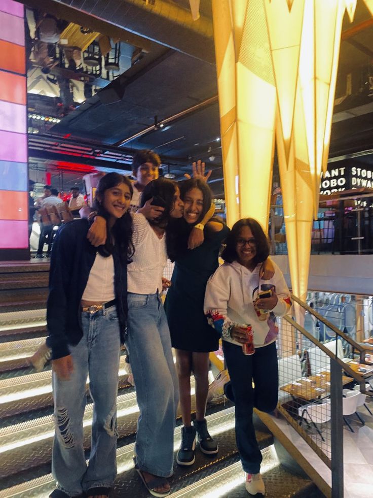 four girls posing for the camera in front of an escalator with their arms around each other