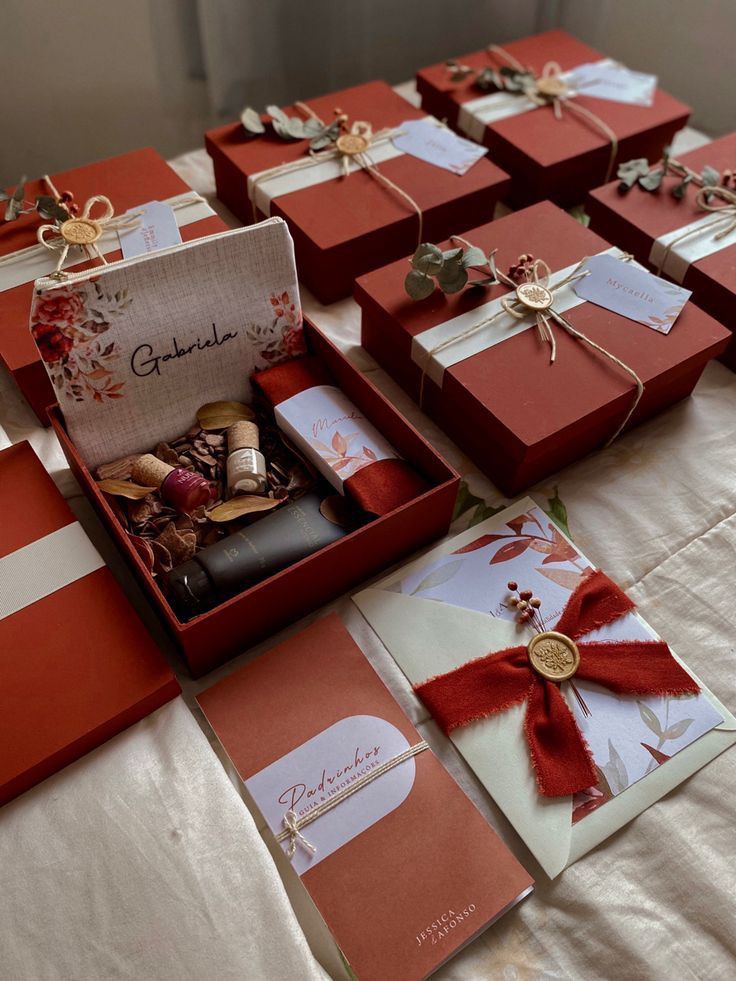 many red boxes with bows and ribbons on a white table cloth covered tablecloths