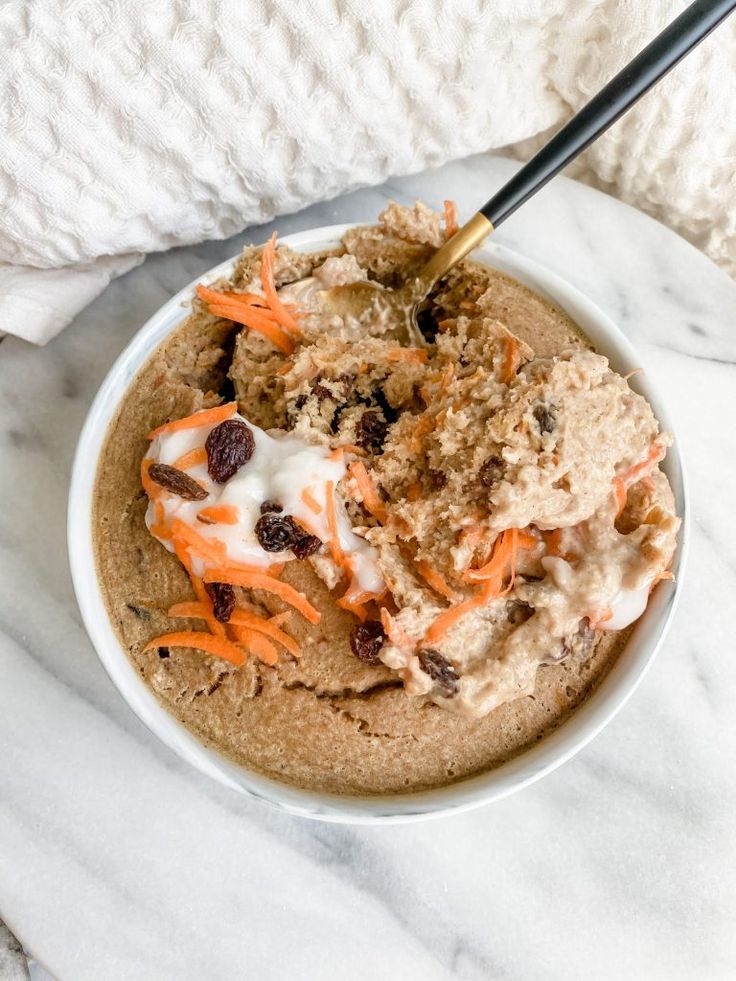 a bowl filled with oatmeal and carrots on top of a white table