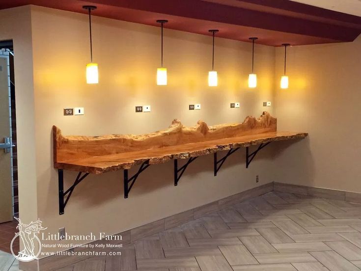 a wooden bench sitting in the middle of a room with four lights hanging from it