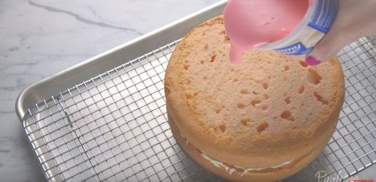 a person pouring milk into a cake on a cooling rack