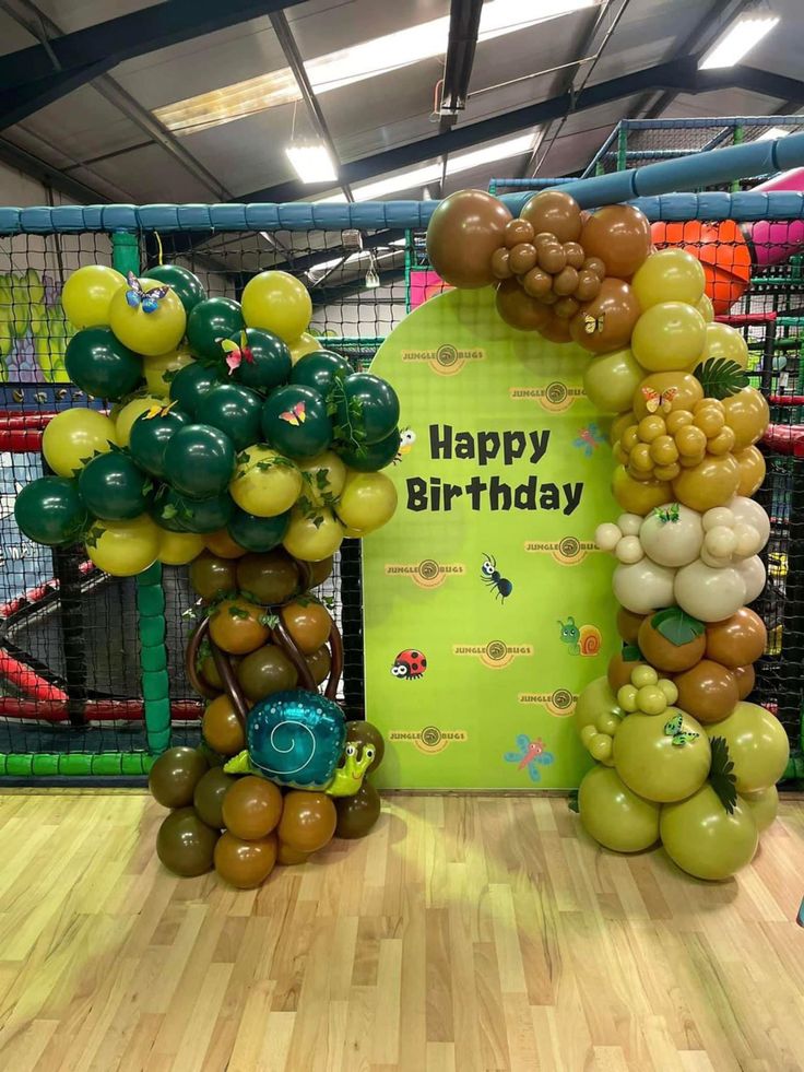 balloons are arranged in the shape of animals and trees for a happy birthday display at a children's play area