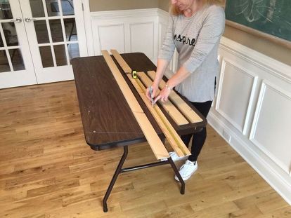 a woman standing next to a table with two pieces of wood on top of it