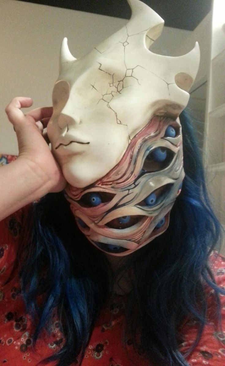 a woman with blue hair is wearing a white mask and has horns on her head