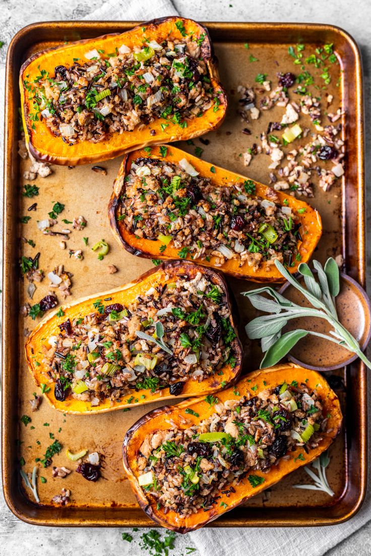 stuffed butternuts with stuffing and herbs on a baking sheet, ready to be eaten