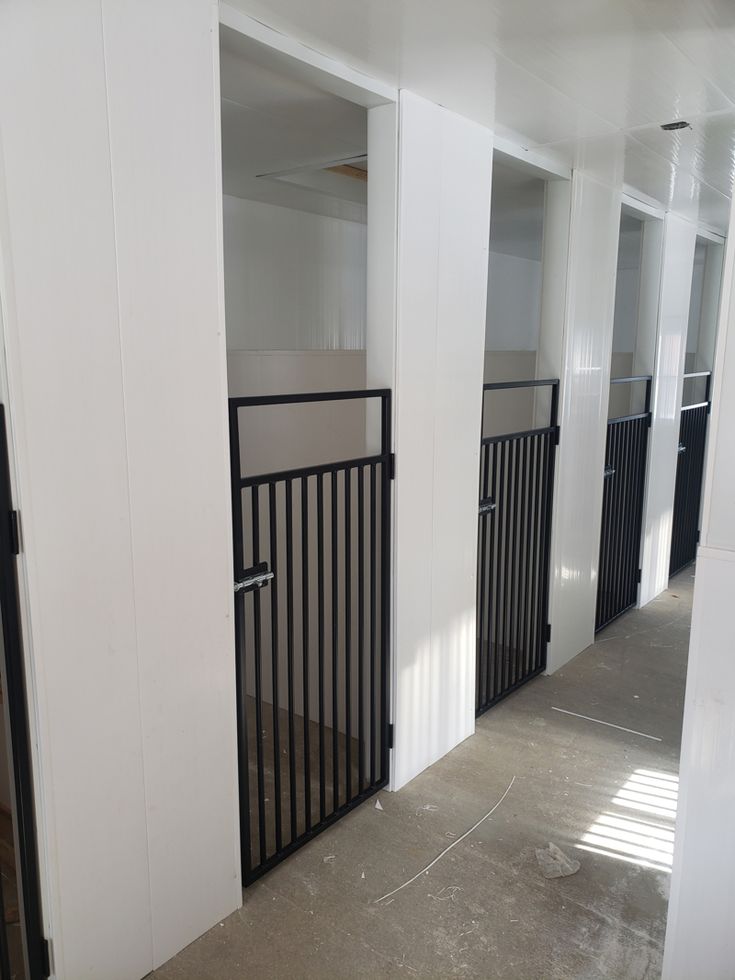 an empty hallway with white walls and black gated entry way leading to another room