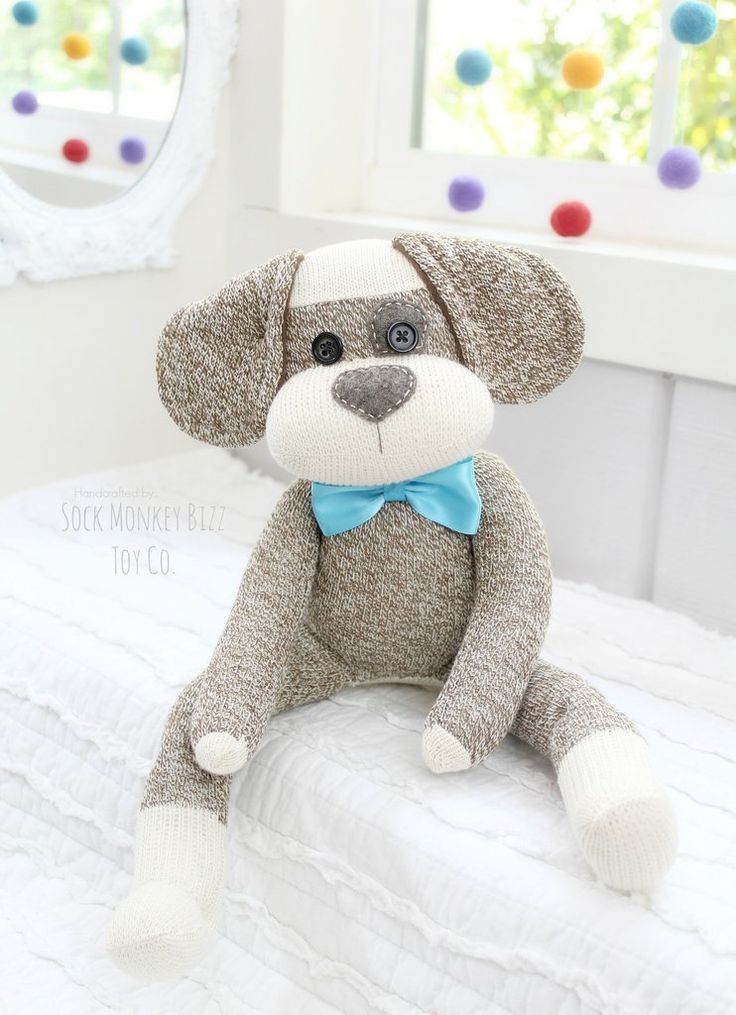 a stuffed monkey with a blue bow tie on it's head sitting on a bed