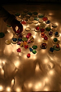 a person standing next to a table covered in plates and cups with lights on them