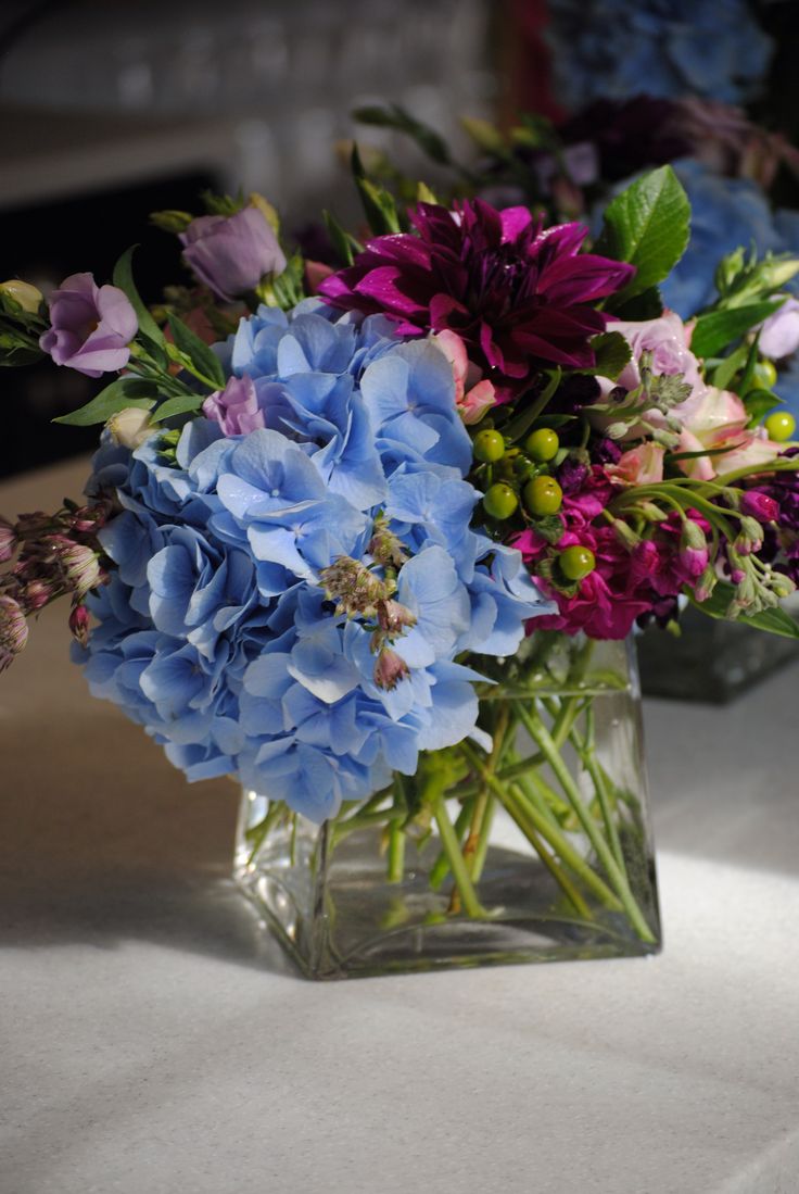 two vases filled with blue and purple flowers