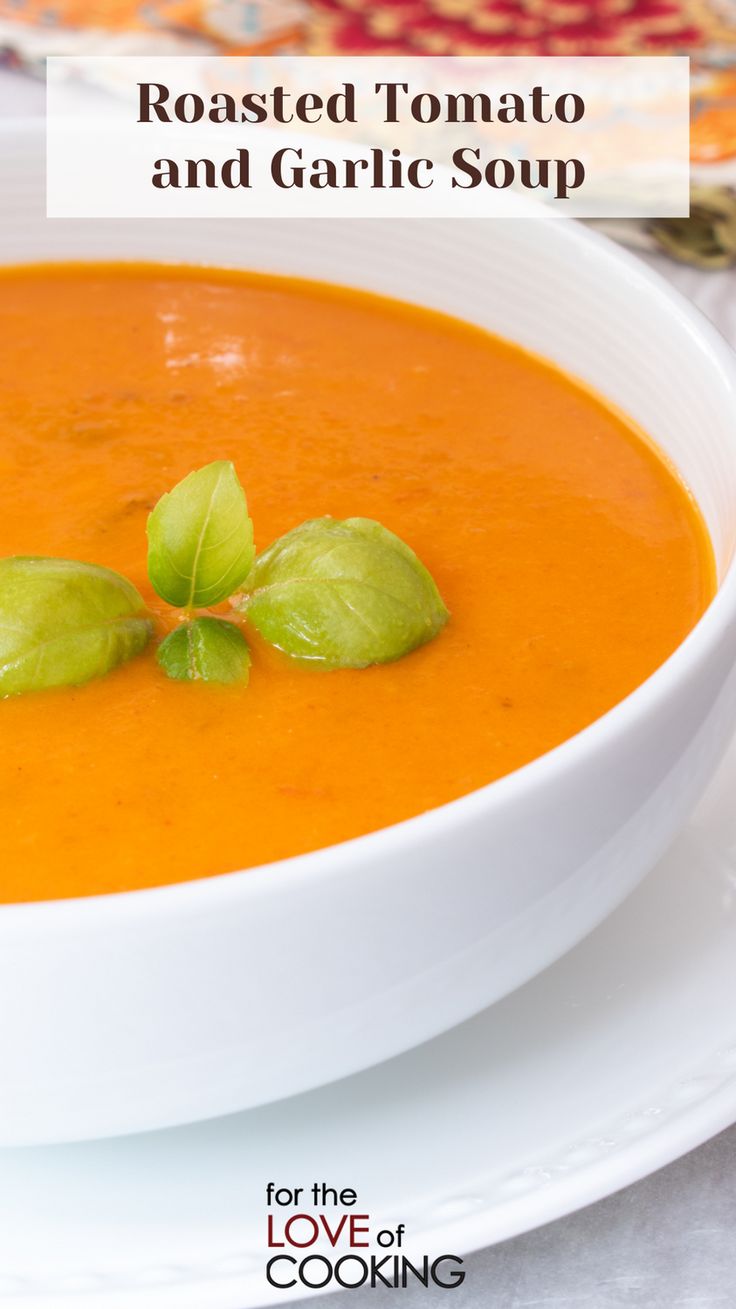 roasted tomato and garlic soup in a white bowl with basil sprig on top