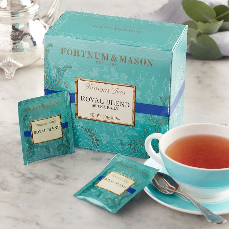 a cup of tea sitting on top of a table next to two packets of royal blend