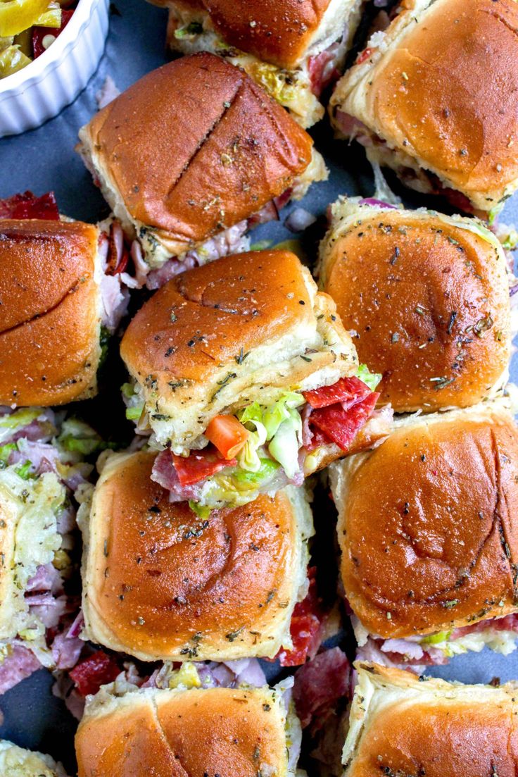 several sliders with different toppings on a blue plate next to a bowl of coleslaw