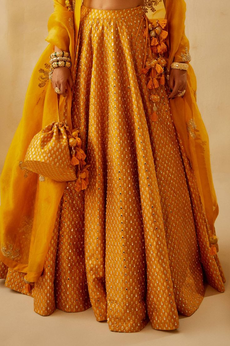 Yellow printed lehenga with embroidered mirror and pearl work. Paired with zardozi embroidered mirror work blouse and organza hand embroidered booti dupatta.
Component: 3
Pattern: Embroidered, Printed
Type Of Work: Floral, Zardozi work, Mirror work
Neckline: High neck
Sleeve Type: Short sleeves
Fabric: Raw silk, Organza, Shantoon
Color: Yellow
Other Details: 
Note: Bag held by model is not for sale
Note: Saree set worn by the other model is not for sale
Occasion: Sangeet, Haldi - Aza Fashions Bhumika Sharma, Printed Lehenga, Mirror Work Blouse, Zardozi Work, Pearl Work, Yellow Print, Silk Organza, Mirror Work, Bridal Lehenga