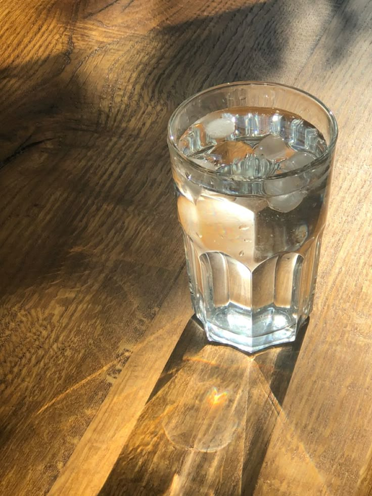 a glass filled with water sitting on top of a wooden table