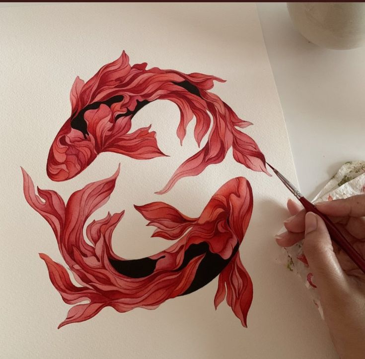 a person is painting a red fish on paper