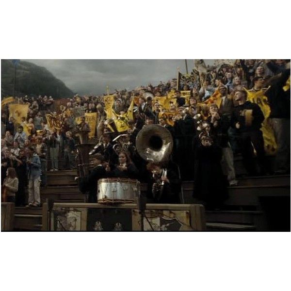 a large group of people standing in front of a stadium filled with yellow flags and banners