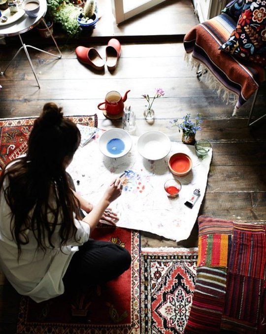 a woman is sitting on the floor painting