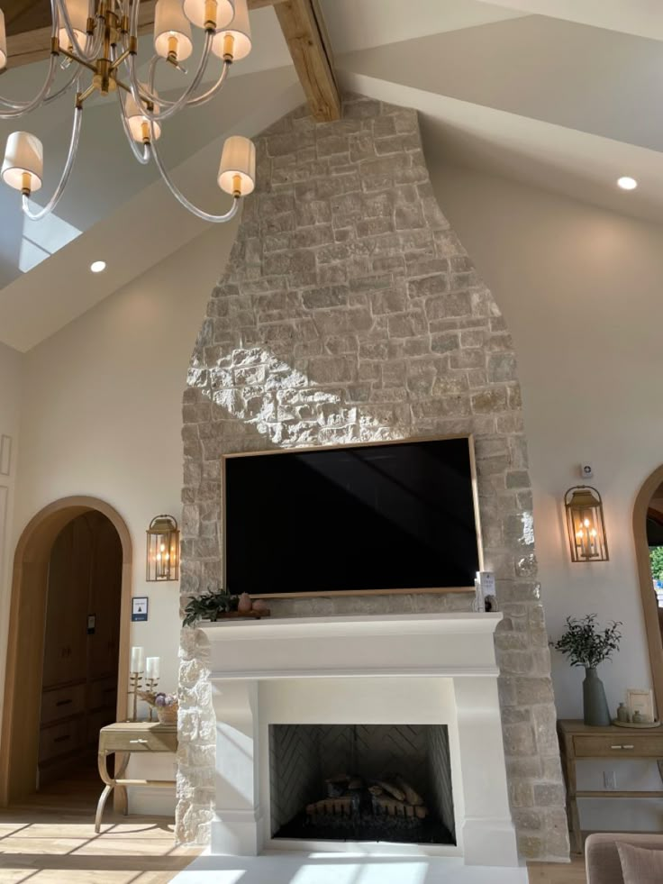 a living room with a fireplace, television and chandelier