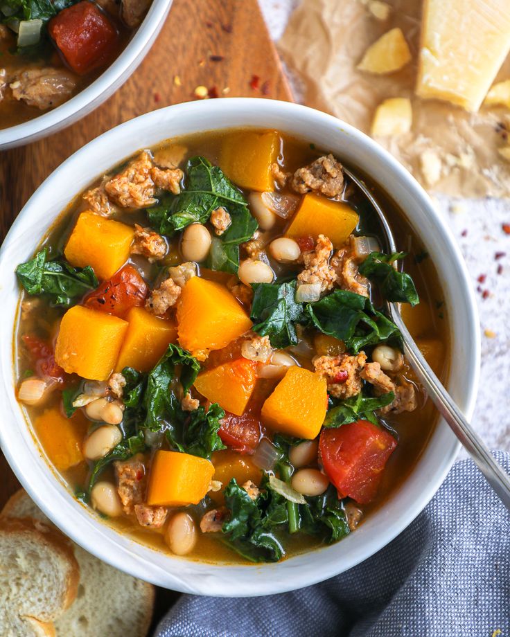 two bowls filled with soup next to bread