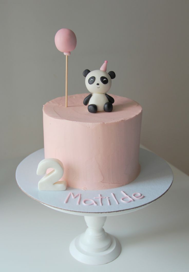 there is a pink cake with a panda on top and a lollipop in the middle