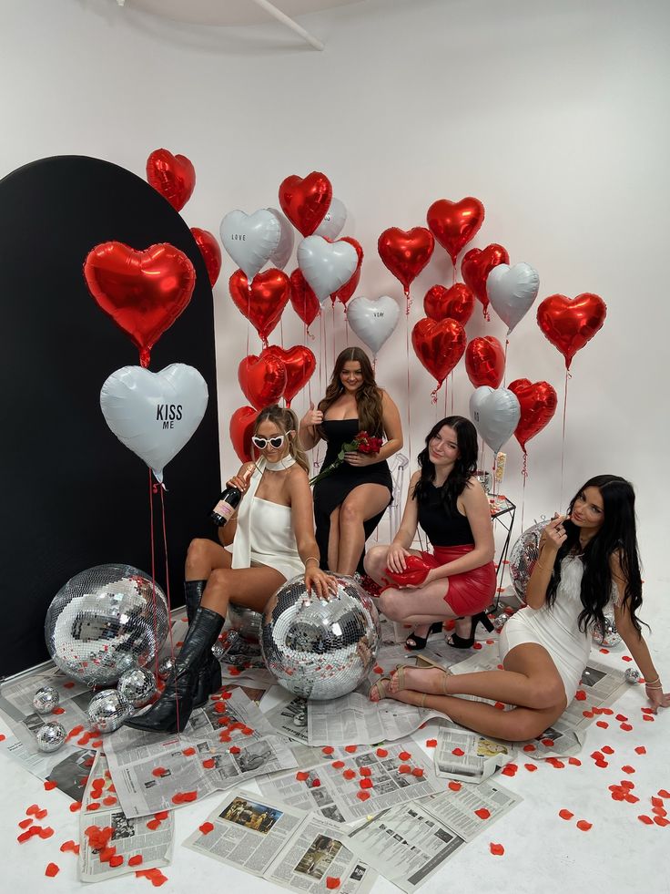 four women sitting on the floor with red and white balloons in front of them,