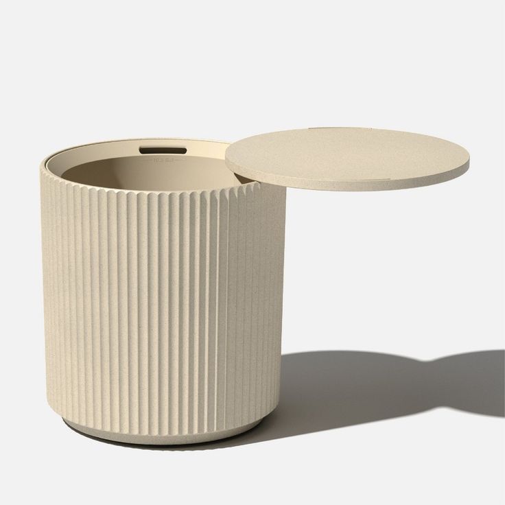 a white vase sitting on top of a table next to a small round container with a lid