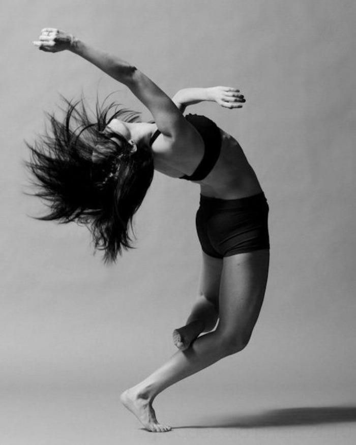 black and white photograph of a woman doing an acrobatic move with her hair blowing in the wind