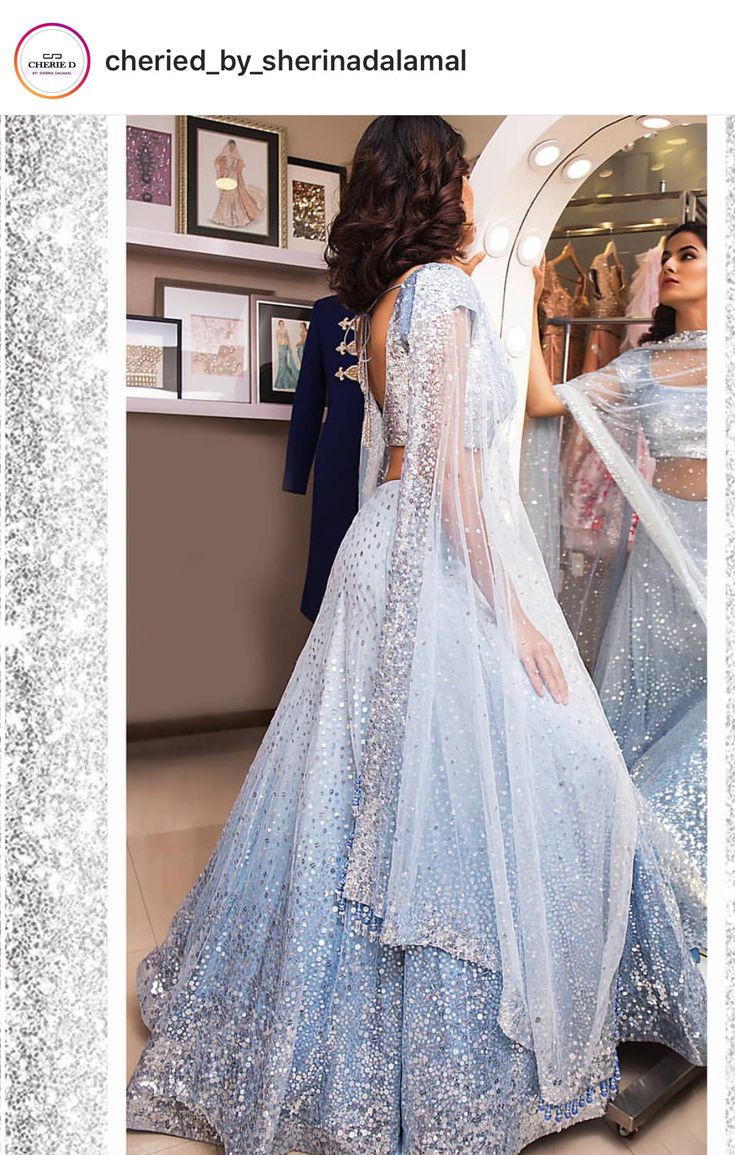 a woman in a blue dress is looking at herself in the mirror with her reflection