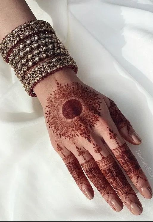 a woman's hand with henna and bracelets on top of her arm