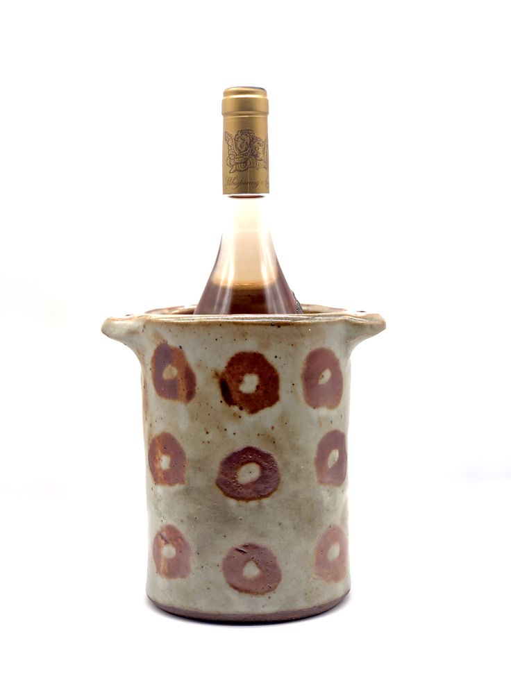 a bottle of wine sitting inside of a ceramic cup