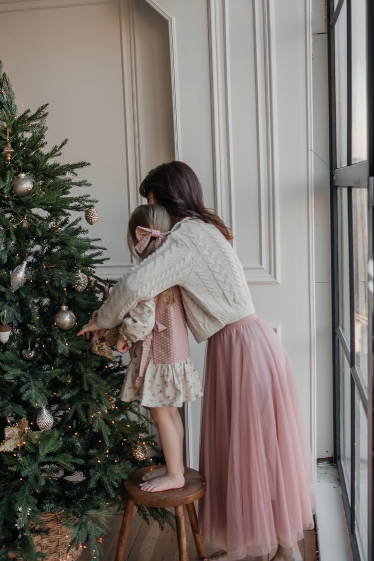 a mother and daughter decorating a christmas tree