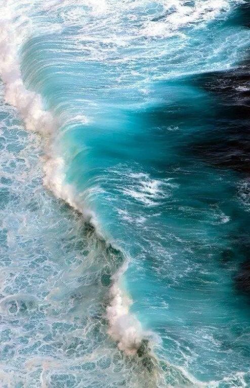 an ocean wave breaking on the beach with foamy blue water and white capped waves