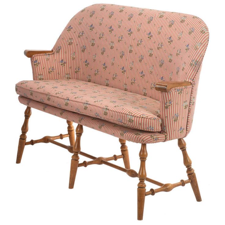 an upholstered chair with wooden legs and pink fabric