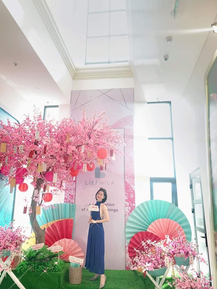 a woman standing in front of a display with pink flowers