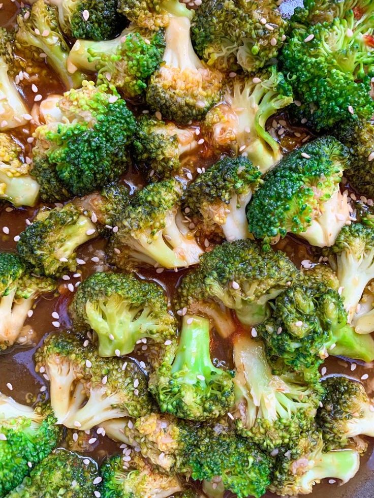 broccoli florets with sesame seeds and brown sauce in a pan on the stove