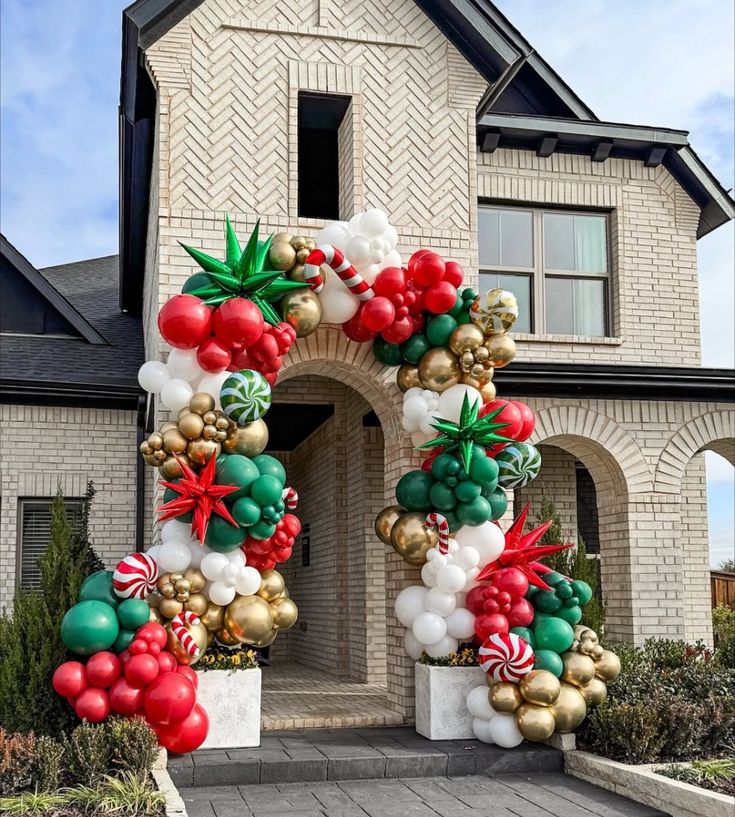 a large balloon arch in front of a house decorated with christmas decorations and balloons for the holiday season