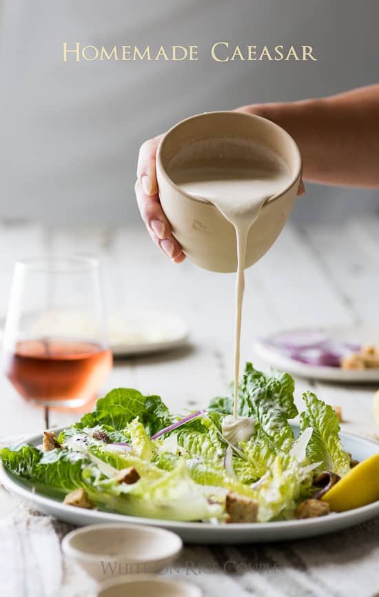 someone pouring dressing into a salad on a plate