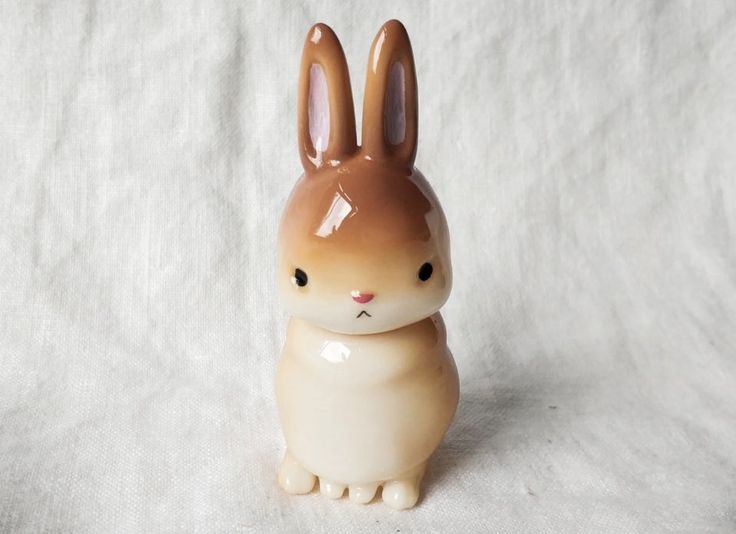 a small toy rabbit sitting on top of a white sheet