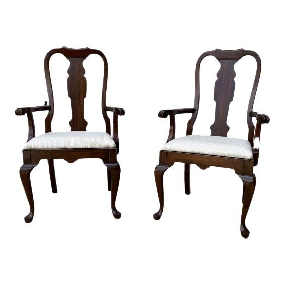 a pair of carved wood chairs with white upholstered seats