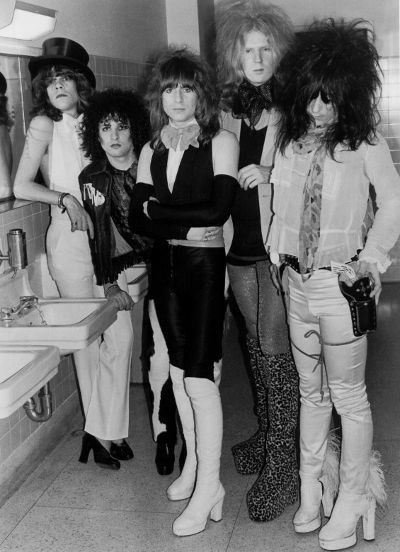 four women standing next to each other in a bathroom with one woman holding her hand on her hip