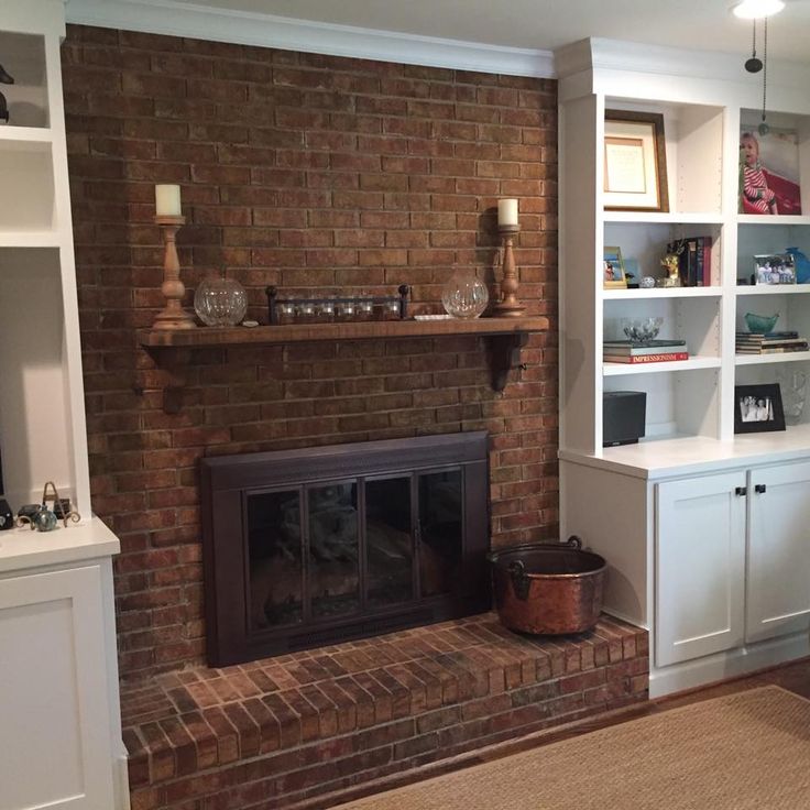 a living room with a brick fireplace and built in bookshelves