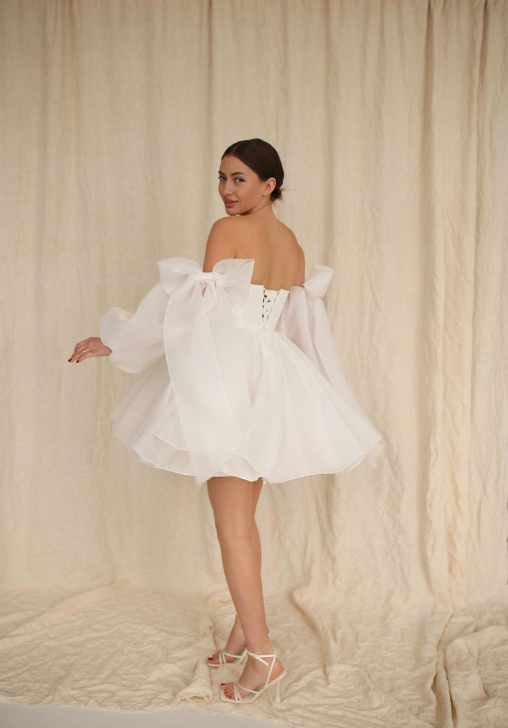 a woman in a white dress is posing for the camera with her hands on her hips