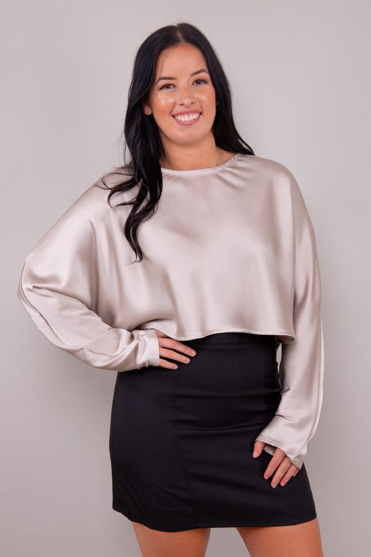 Crafted from the finest satin, this blouse exudes a luxurious allure that's hard to resist. The silky-smooth fabric drapes gracefully, and the long sleeves add a touch of classic charm. The cropped length is not only on-trend but also versatile, allowing you to pair it with high-waisted skirts, pants, or jeans for a look that's both chic and contemporary. Whether you're dressing up for a special occasion or elevating your everyday style, this blouse is your go-to choice. Its simplicity is its st Sleek Evening Blouse With Satin Finish, Sleek Satin Finish Evening Blouse, Chic Satin Finish Blouse For Evening, Chic Satin Finish Evening Blouse, Chic Satin Evening Blouse, Sleek Satin Blouse For Night Out, Chic Satin Finish Tops For Evening, Chic Satin Finish Tops For Night Out, Long Sleeve Tops With Satin Finish For Formal Occasions