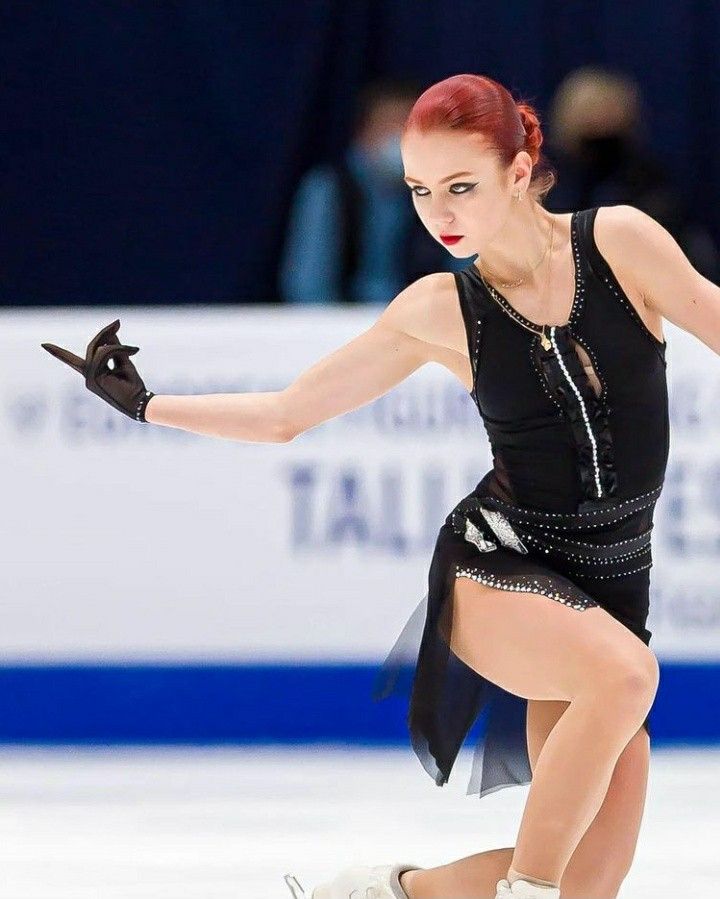 a woman skating on an ice rink wearing a black dress and holding her arms out