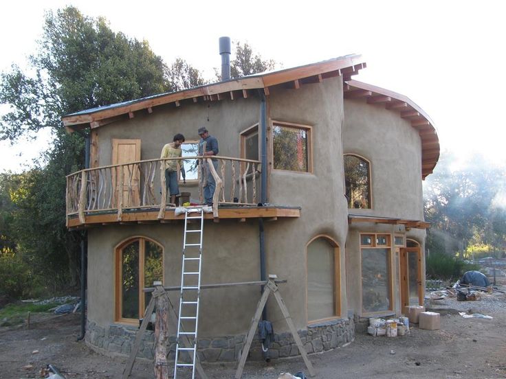 two men are standing on the roof of a house that is being built with wood