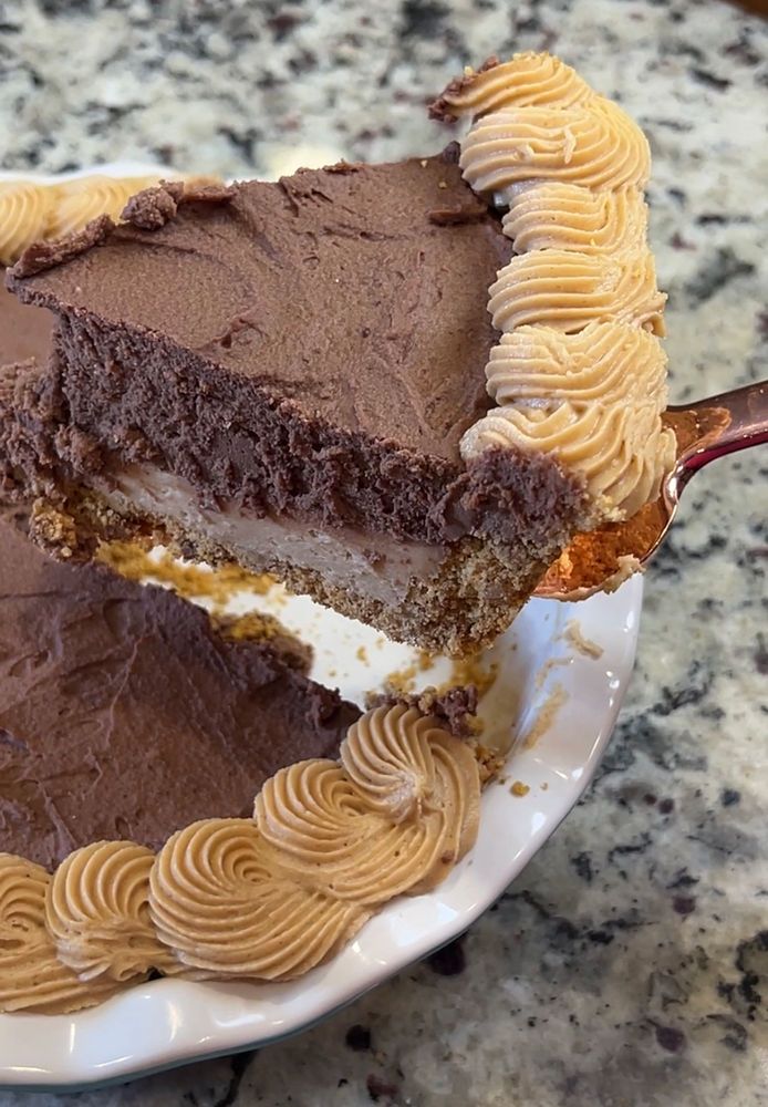 a piece of cake on a white plate with a fork in it and some chocolate frosting